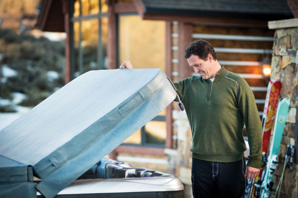 Man lifting the cover of a Sundance® Hot Tub - Idaho Spas explains the three signs you should replace your hot tub cover.