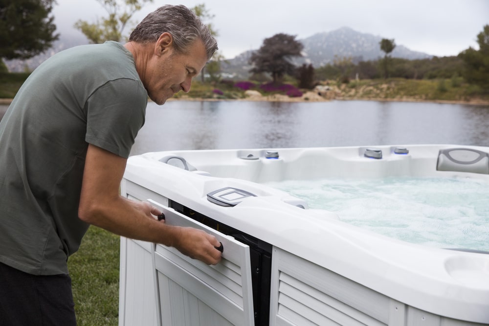 man opening side door of hot tub for maintenance