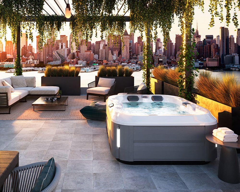 A luxurious rooftop terrace with modern furniture and a plug and play hot tub, overlooking a stunning cityscape during sunset.